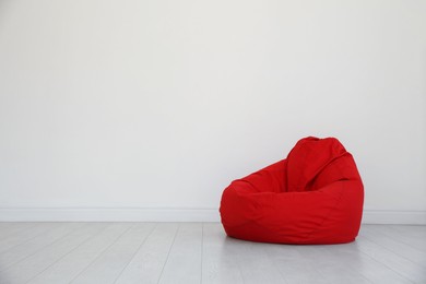 Photo of Red bean bag chair near light wall in room. Space for text