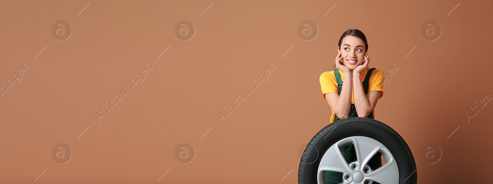 Image of Seller in uniform with car tire on brown background, space for text. Banner design