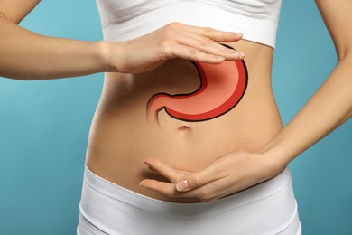 Woman with image of healthy stomach on blue background, closeup
