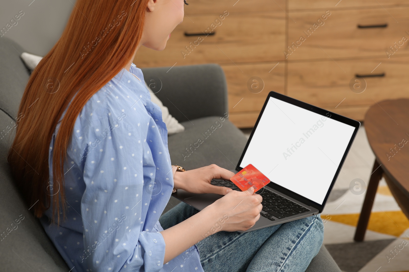 Photo of Woman with credit card using laptop for online shopping on sofa at home, closeup