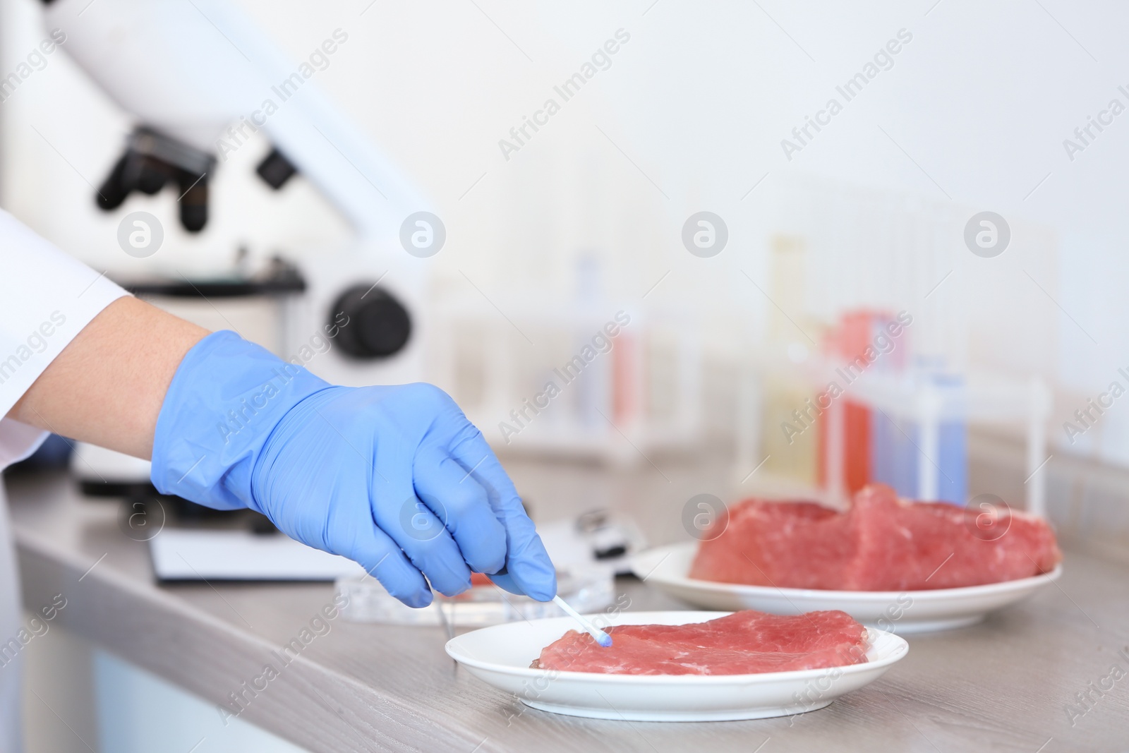 Photo of Scientist inspecting meat at table in laboratory, closeup. Food quality control