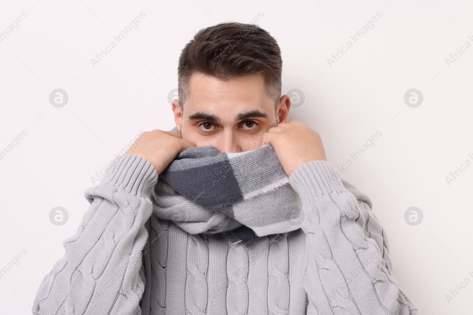 Photo of Man hiding in warm scarf on light background