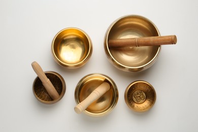 Photo of Golden singing bowls and mallets on white background, flat lay