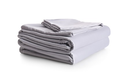 Stack of clean silky bed linen isolated on white