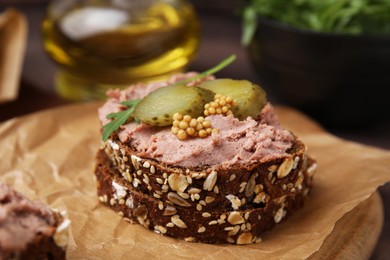 Photo of Delicious liverwurst sandwich with pickled cucumber and mustard on table, closeup
