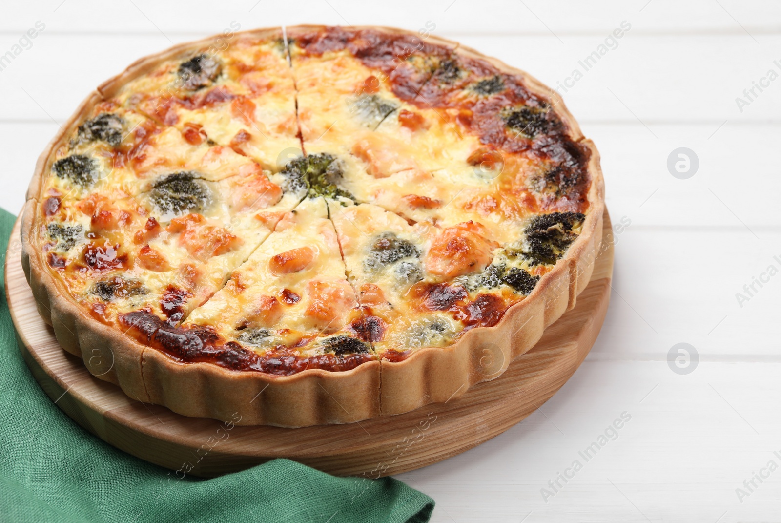 Photo of Delicious homemade quiche with salmon and broccoli on white wooden table