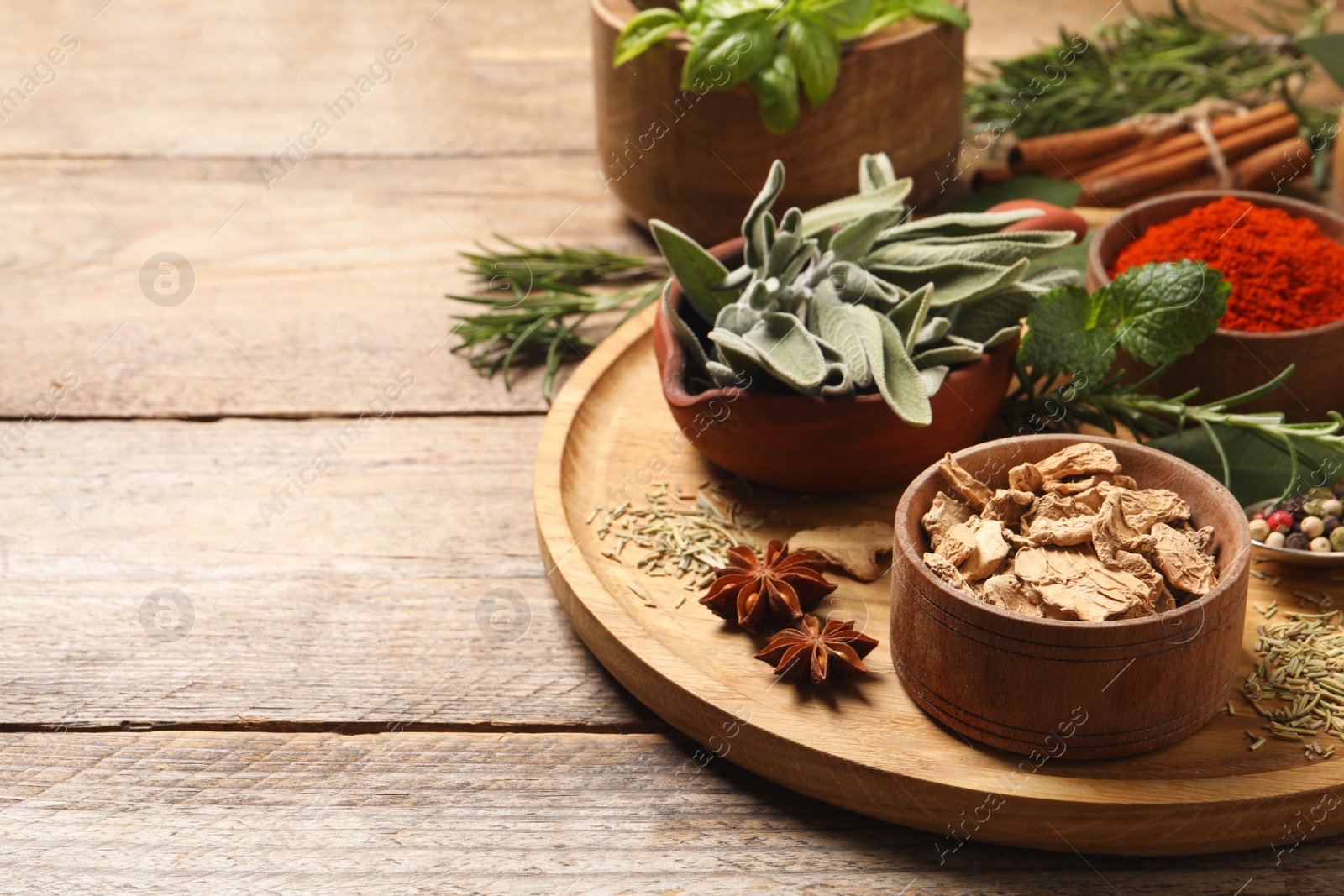 Photo of Different herbs and spices on wooden table. Space for text