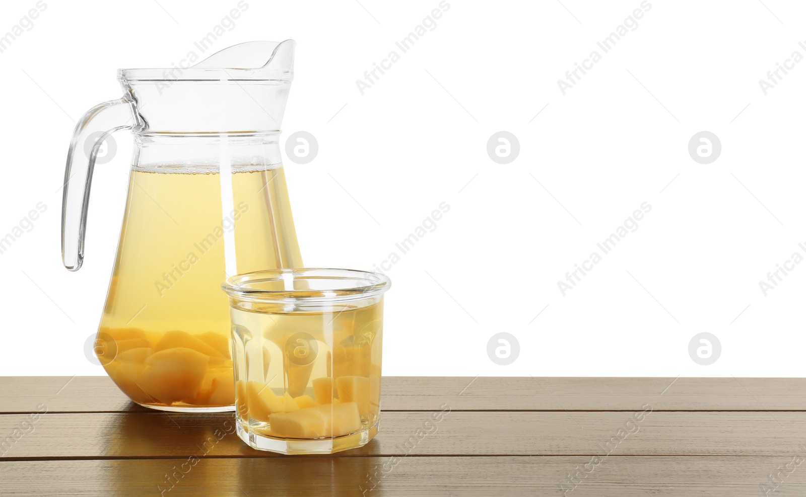 Photo of Delicious quince drink in jug and glass on wooden table against white background
