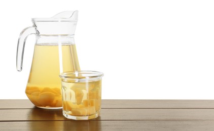 Delicious quince drink in jug and glass on wooden table against white background