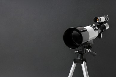 Tripod with modern telescope on black background, closeup. Space for text