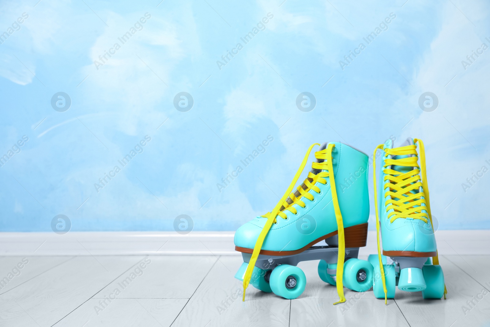 Photo of Vintage roller skates on floor near color wall. Space for text