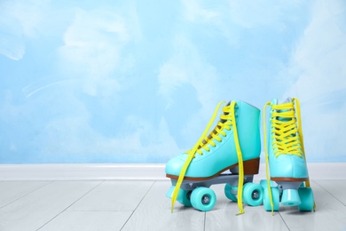 Photo of Vintage roller skates on floor near color wall. Space for text