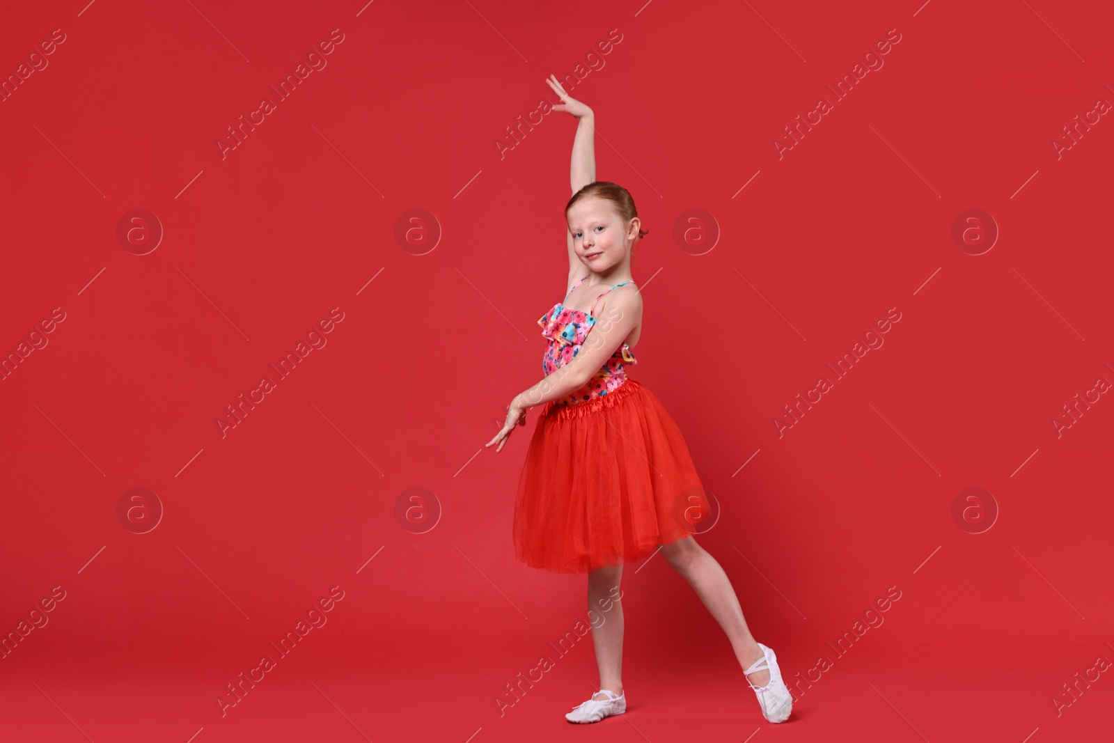 Photo of Cute little girl dancing on red background