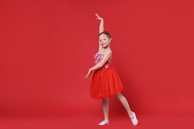 Cute little girl dancing on red background