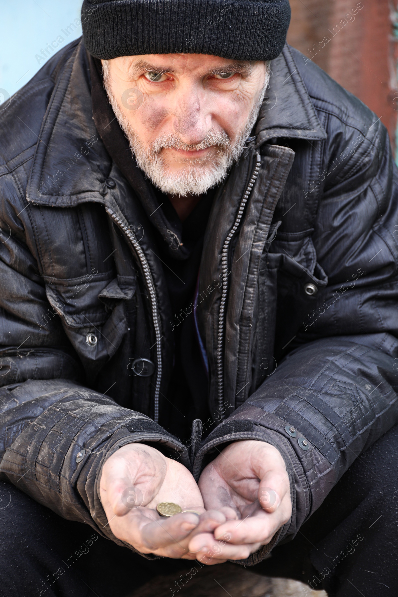 Photo of Poor homeless senior man holding coins outdoors