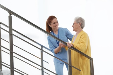 Photo of Nurse assisting senior woman to go up stairs at hospital