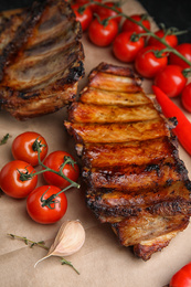 Photo of Tasty grilled ribs with tomatoes on table
