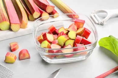 Photo of Whole and cut rhubarb stalks on white table