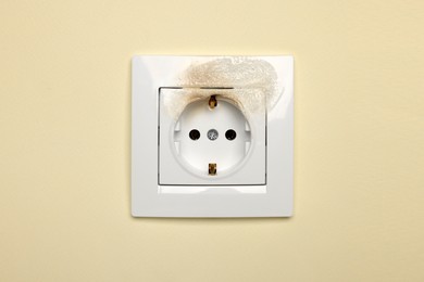 Photo of Burnt power socket on beige wall. Electrical short circuit