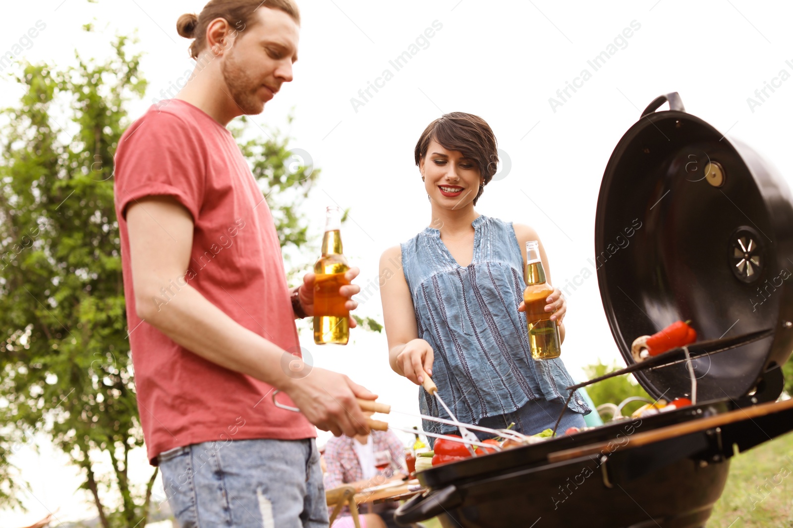 Photo of Young people having barbecue with modern grill outdoors