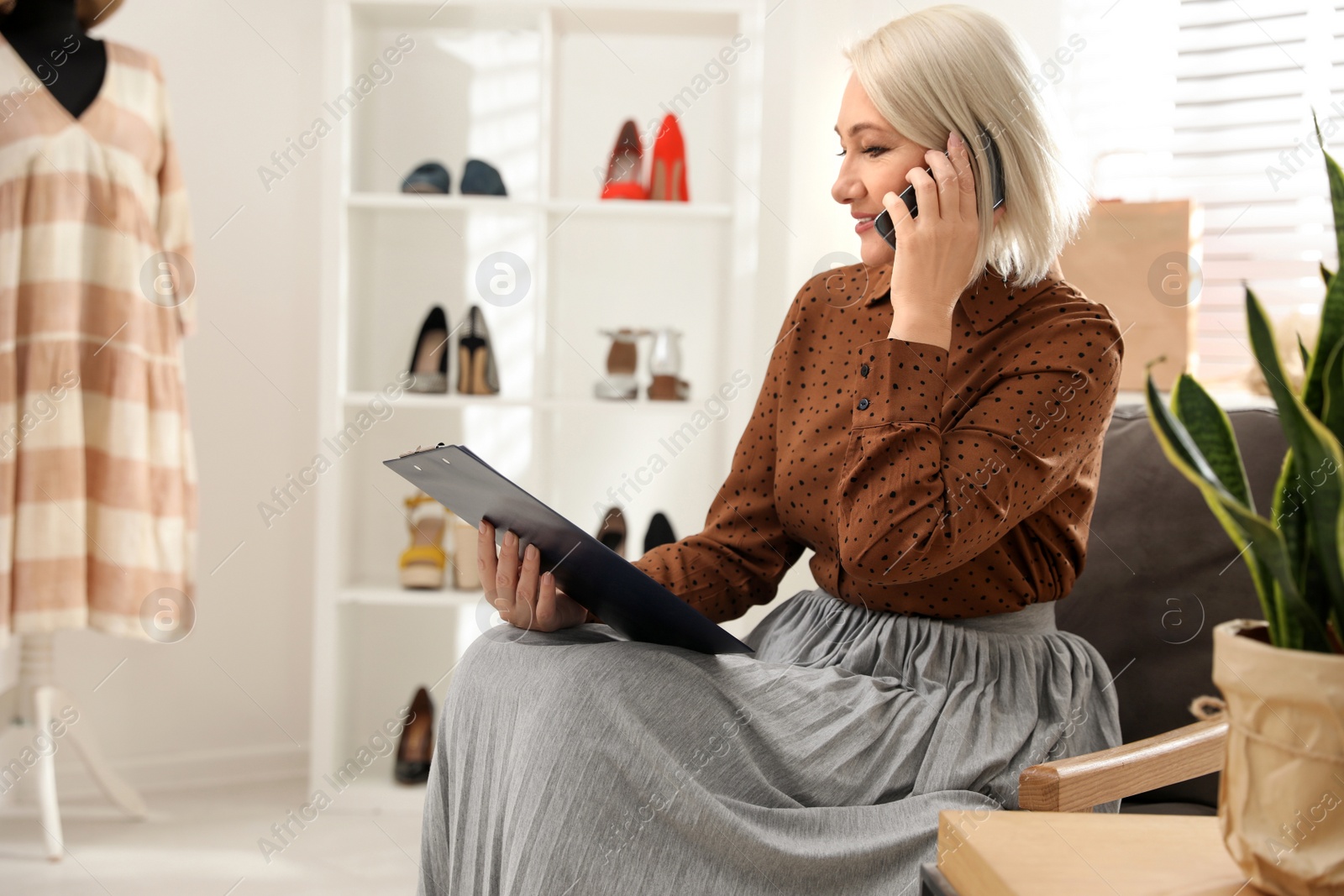 Photo of Female business owner talking on phone in boutique