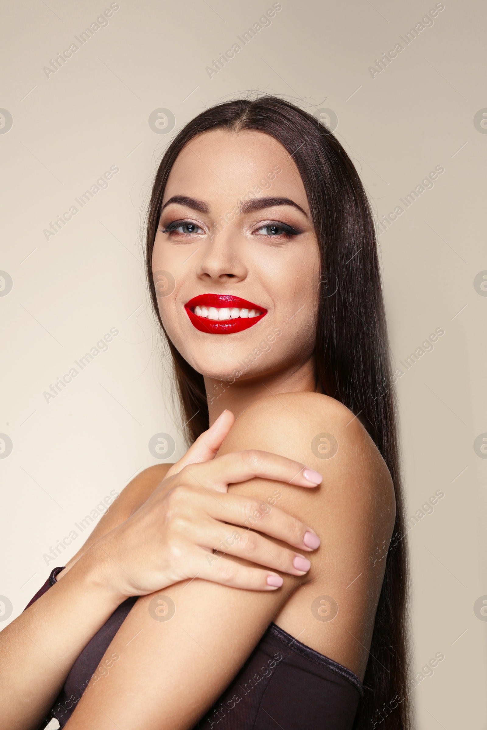 Photo of Portrait of beautiful young woman with red glossy lips on color background