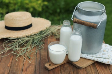 Photo of Fresh milk on wooden table outdoors. Space for text