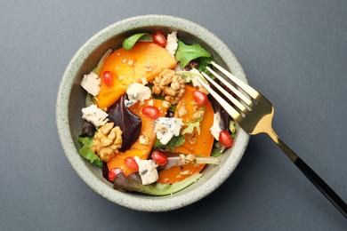 Photo of Delicious persimmon salad with cheese and pomegranate on grey table, top view