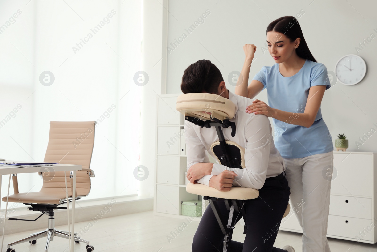 Photo of Man receiving massage in modern chair indoors