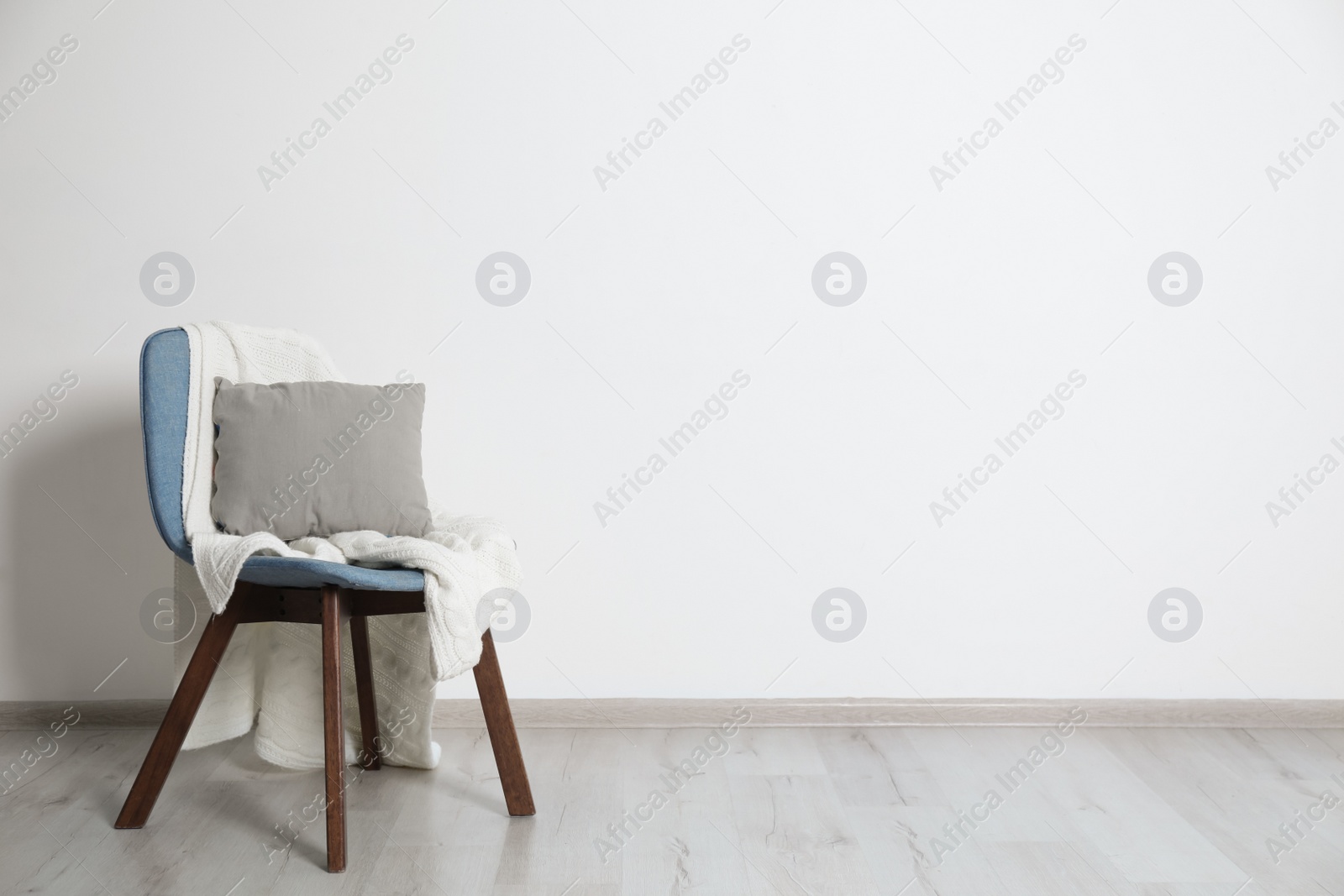 Photo of Stylish chair with pillow and plaid near white wall. Idea for interior design