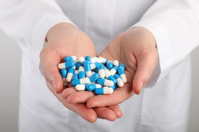 Woman holding many antibiotic pills, closeup. Medicinal treatment