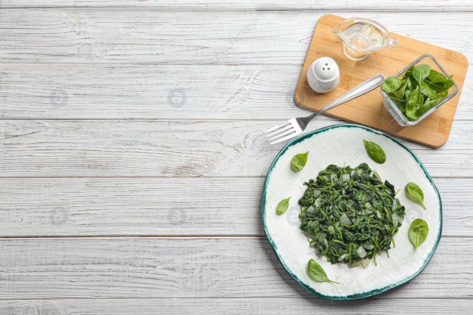 Photo of Flat lay composition with tasty cooked spinach and space for text on white wooden table. Healthy food