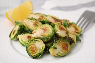 Photo of Delicious roasted Brussels sprouts and slice of lemon on table, closeup