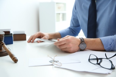 Notary working with tablet at table in office, closeup. Law and justice concept