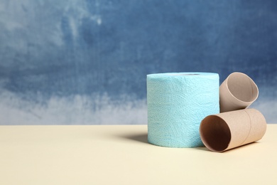 Photo of Full and empty toilet paper rolls on table against color background. Space for text