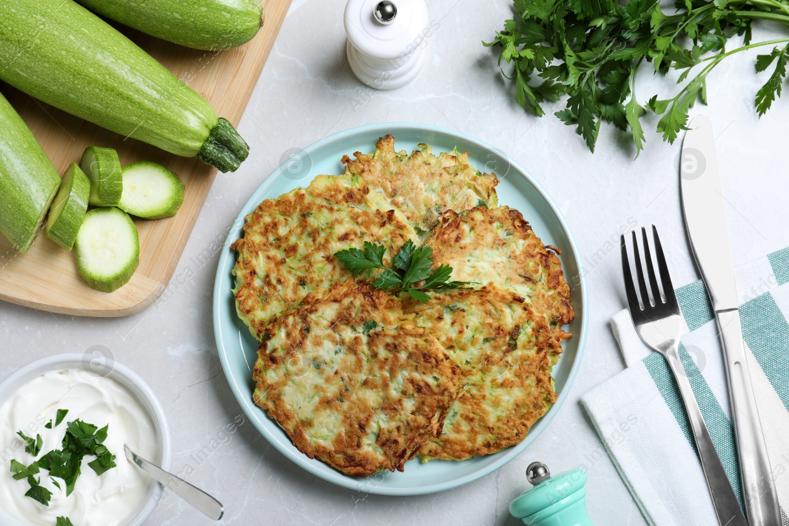 Photo of Delicious zucchini fritters served on light table, flat lay