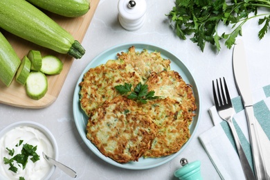 Delicious zucchini fritters served on light table, flat lay