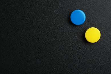 Photo of Bright magnets on black background, top view with space for text