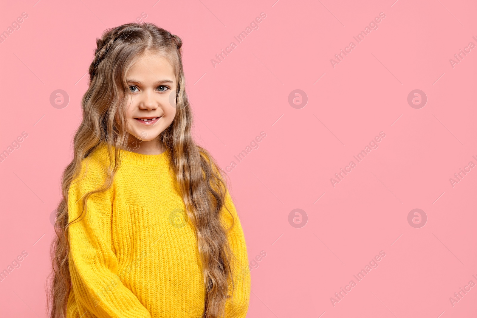 Photo of Cute little girl with braided hair on pink background. Space for text