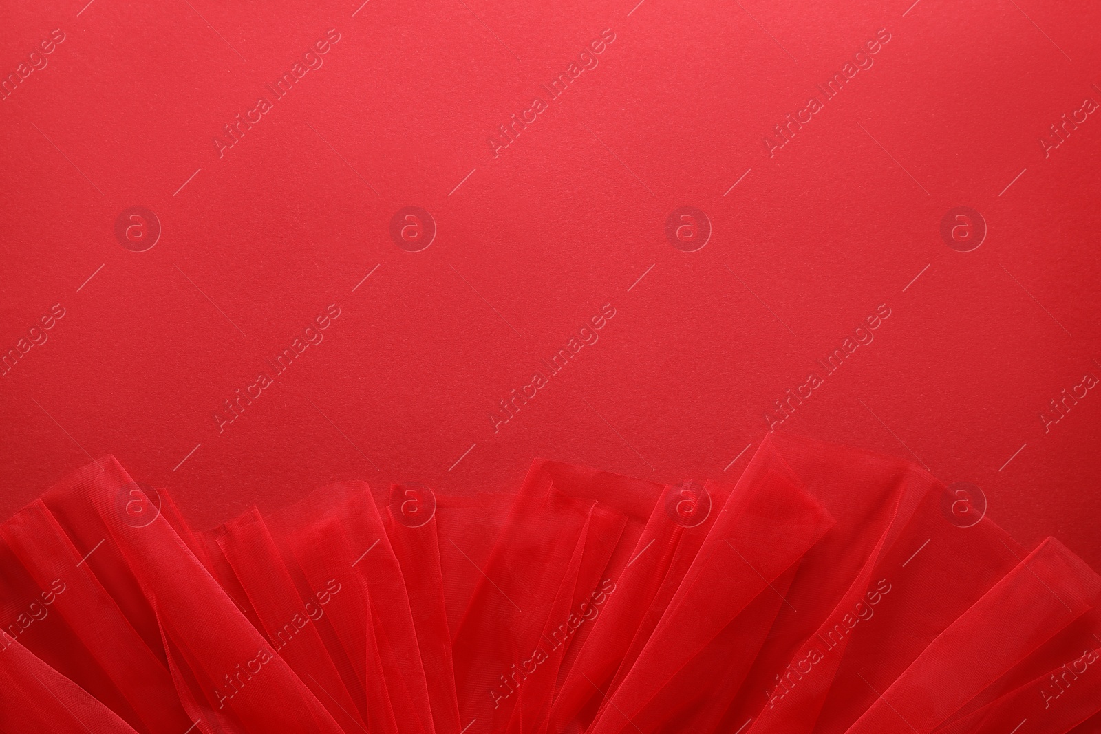 Photo of Beautiful tulle fabric on red background, top view. Space for text