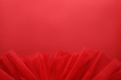 Photo of Beautiful tulle fabric on red background, top view. Space for text