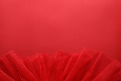 Beautiful tulle fabric on red background, top view. Space for text