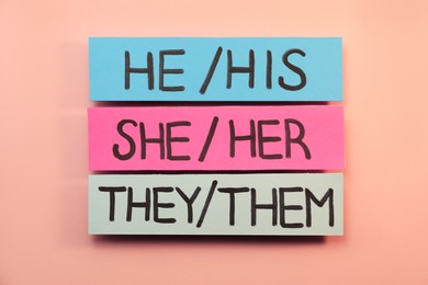 Photo of Sheets of paper with pronouns on pink background, flat lay. Gender equality