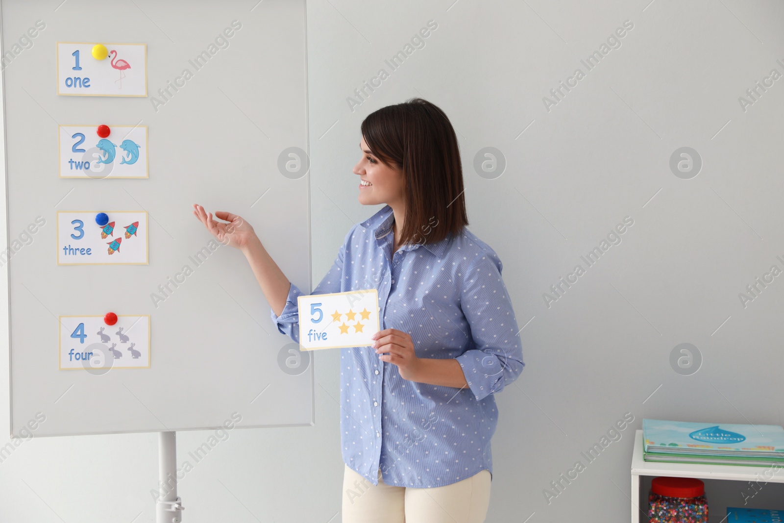 Photo of Happy female English teacher giving lesson indoors. Early childhood education