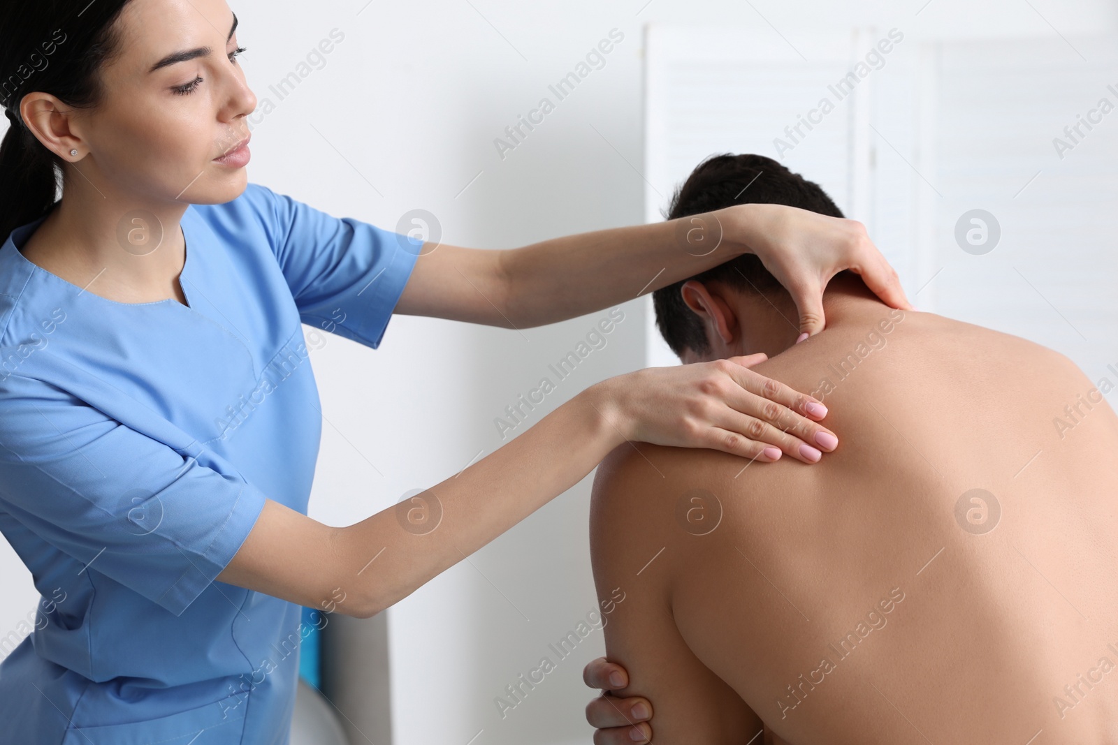 Photo of Orthopedist examining man's neck in clinic. Scoliosis treatment