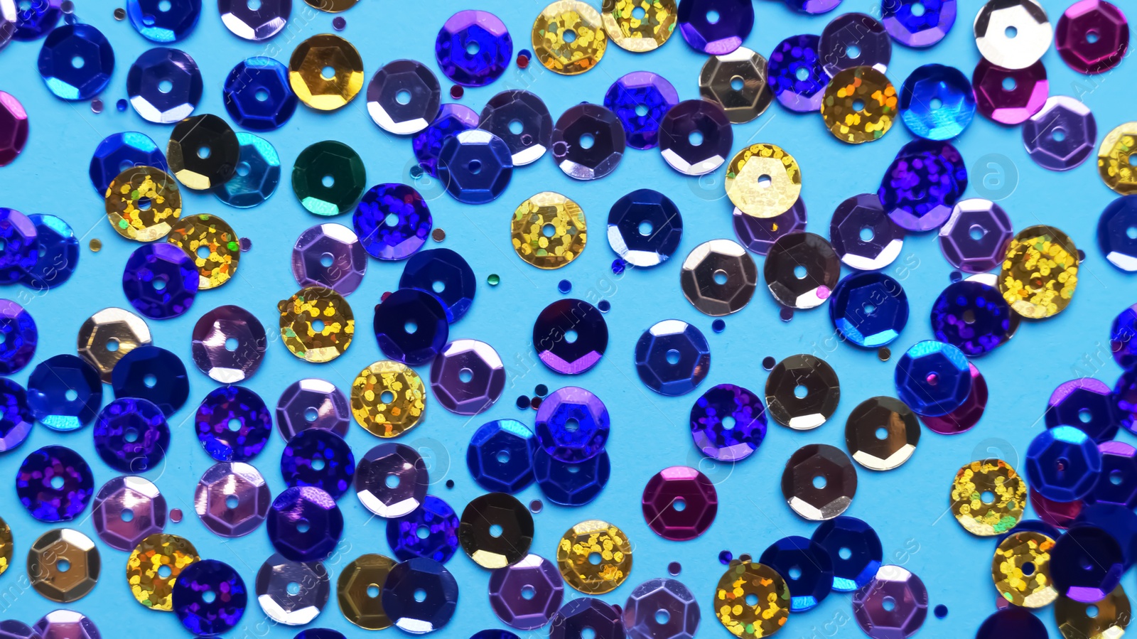 Photo of Many different sequins on light blue background, flat lay