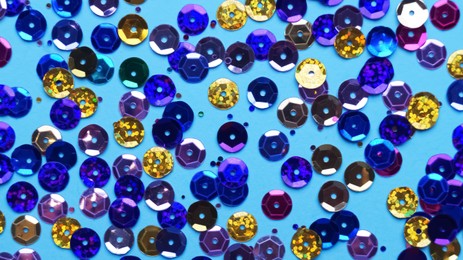 Photo of Many different sequins on light blue background, flat lay