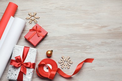 Photo of Flat lay composition with beautiful Christmas gift boxes and wrapping paper on white wooden table. Space for text