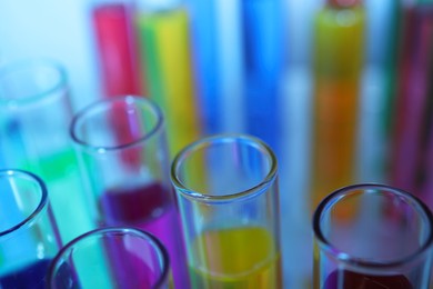 Many test tubes with colorful liquids on blurred background, closeup