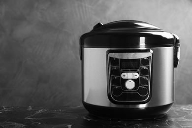 Photo of Modern powerful multi cooker on table against grey background. Space for text